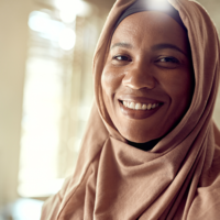 happy-muslim-businesswoman-looking-camera-while-working-office